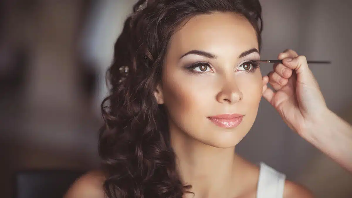 A bride having her makeup applied by a makeup artist